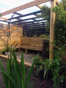 A contemporary garden pergola with seating and greenery
